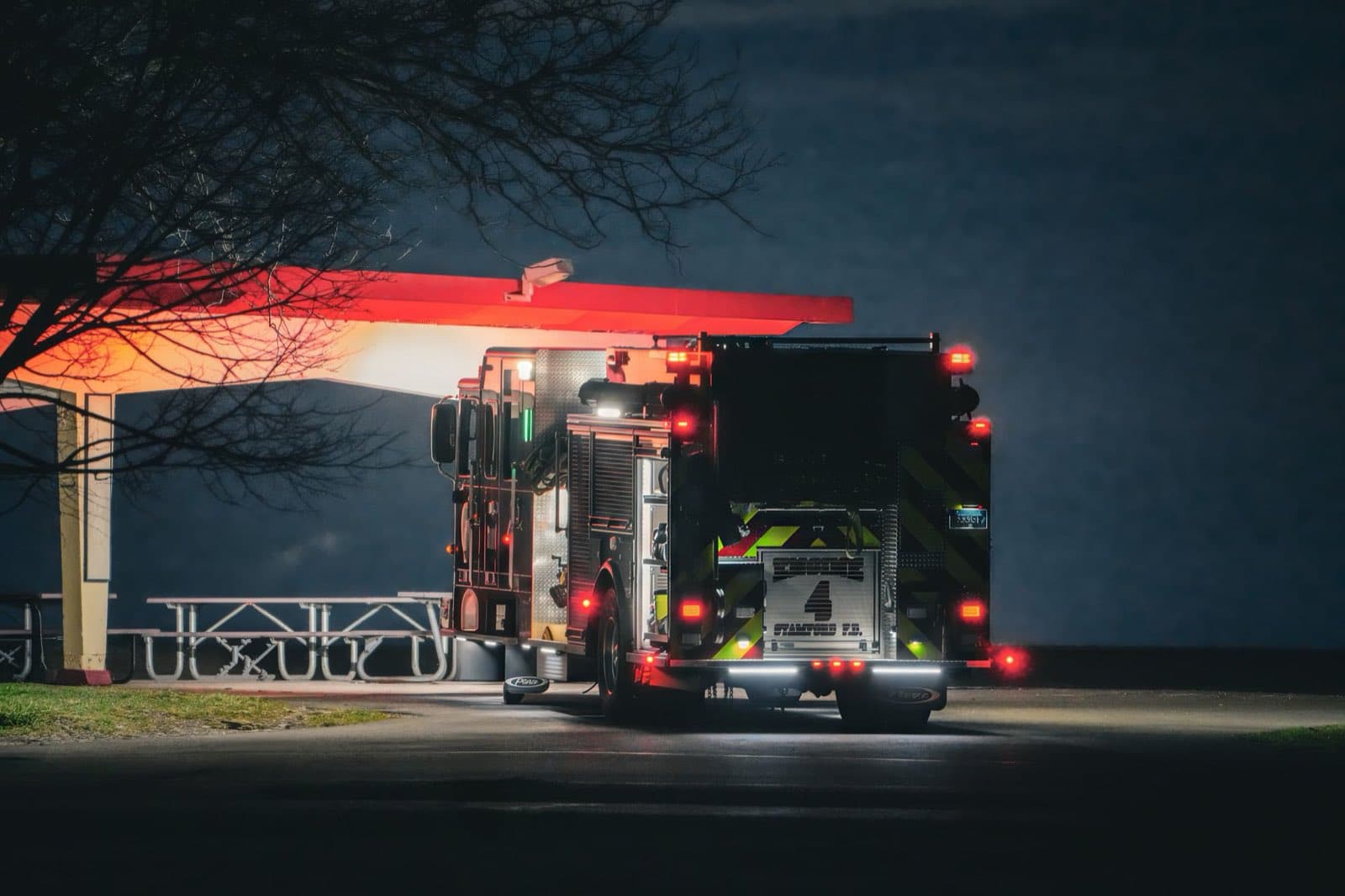 A fire engine parked at night under a lit station canopy