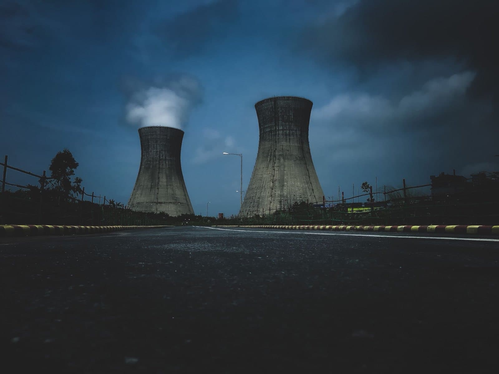 Two power plant cooling towers under a deep blue evening sky