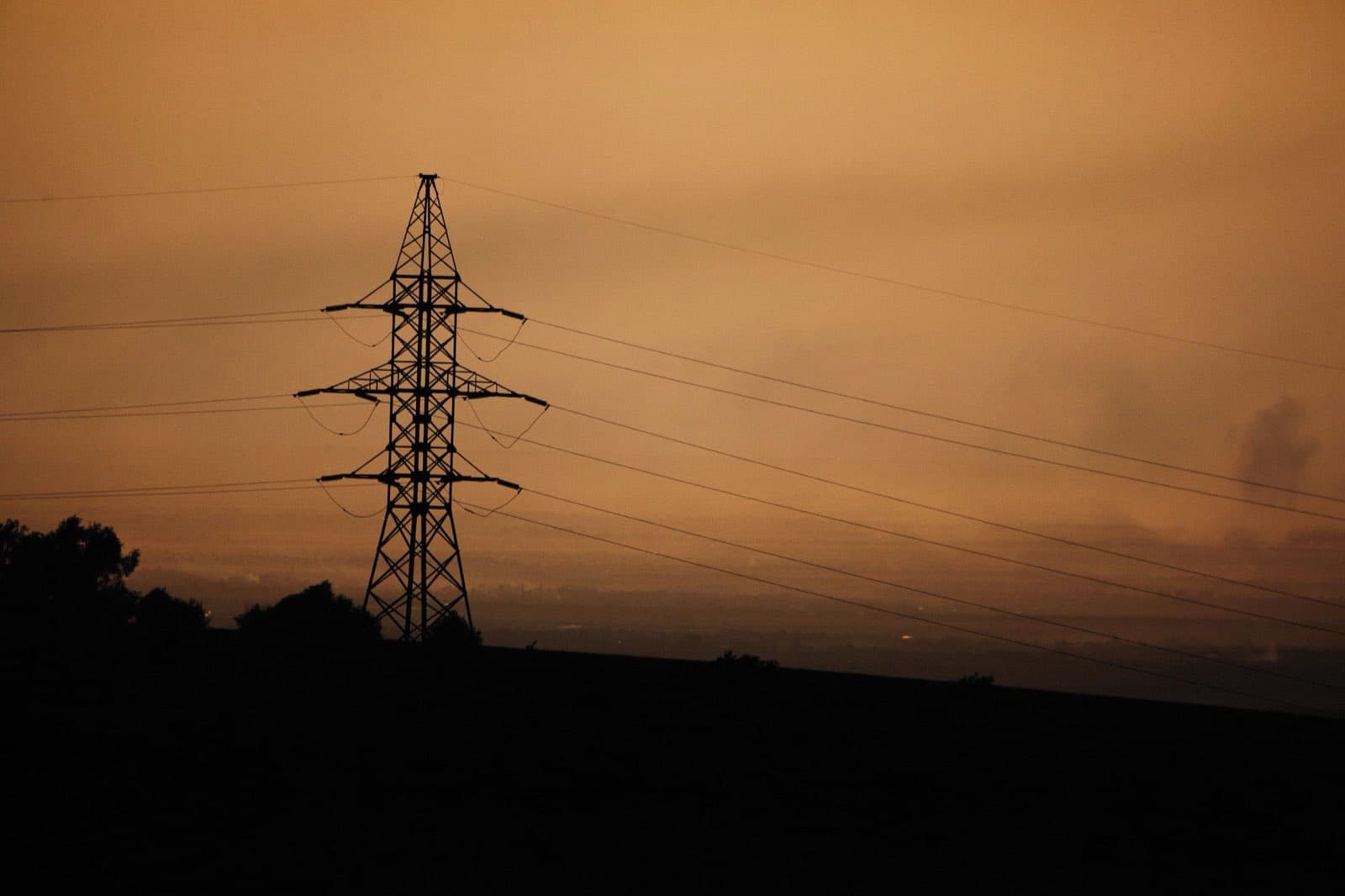 A transmission tower silhouetted against an amber dusk sky